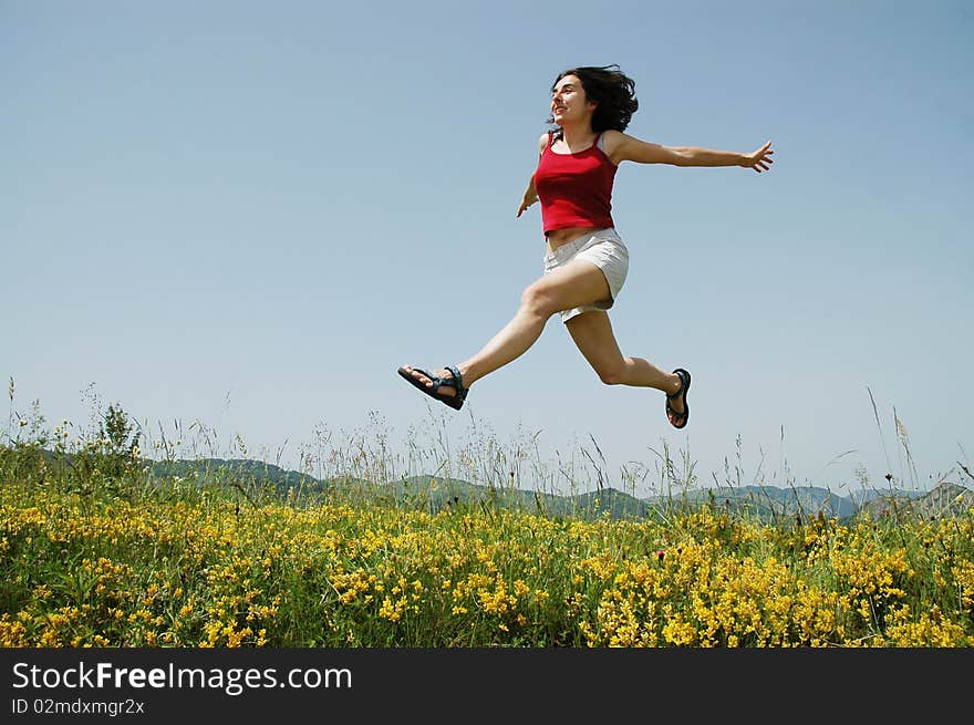 Beautiful young girl jumping on a yellow field