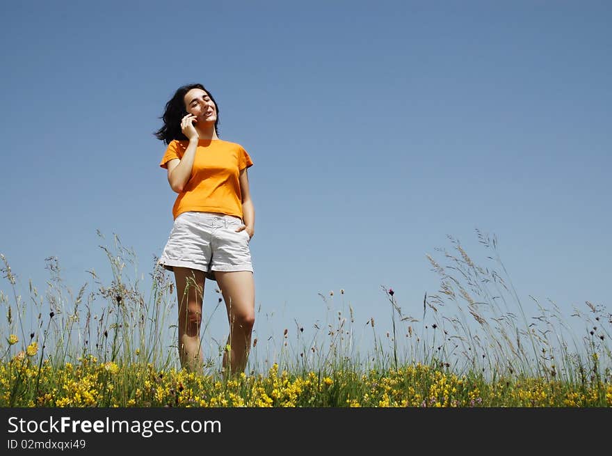 Happy woman enjoying the outdoors using her cell phone in orange T-shirt