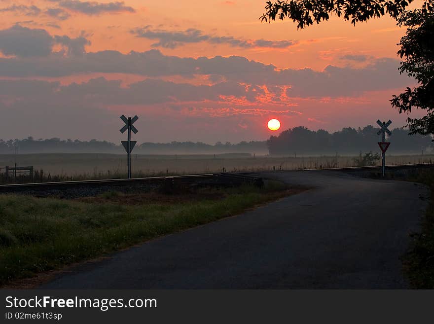 Rural sunrise with road and railroad crossing