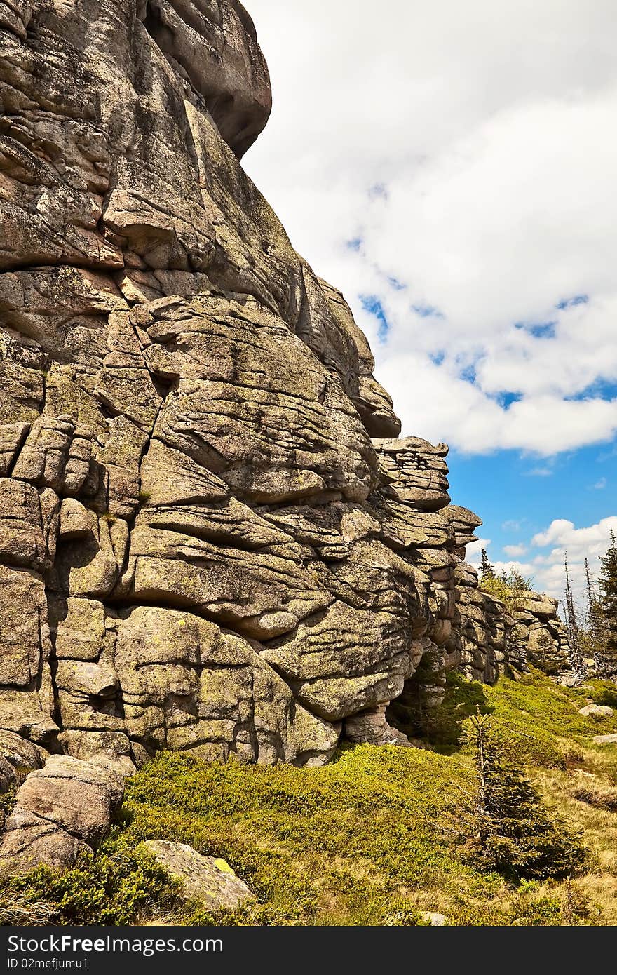 Rock wall close-up photo over blue sky and clouds. Rock wall close-up photo over blue sky and clouds.