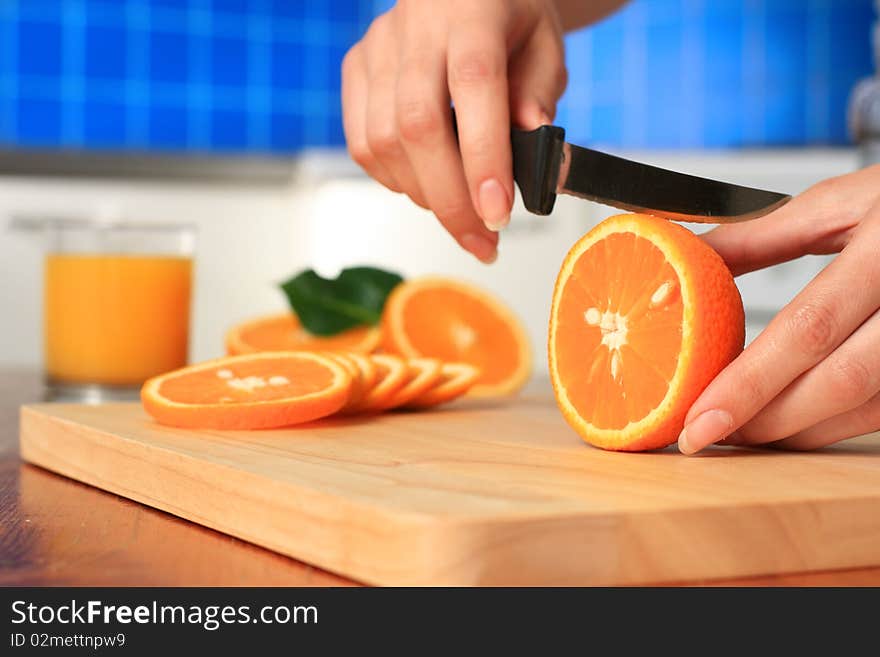 Female chopping juicy orange on the kitchen. Female chopping juicy orange on the kitchen.