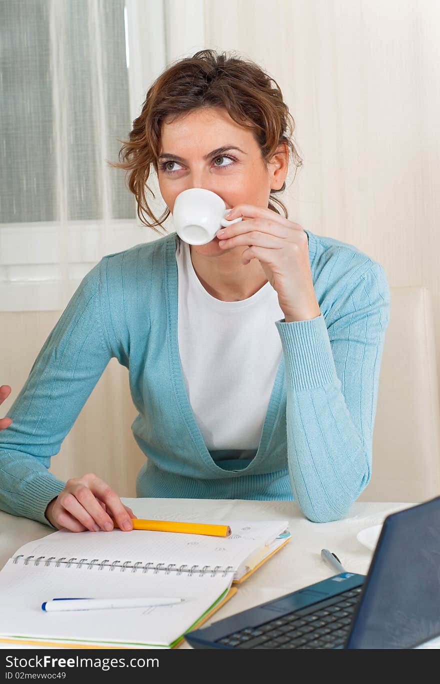 A young woman takes a coffee break from her computer and notebook. A young woman takes a coffee break from her computer and notebook.