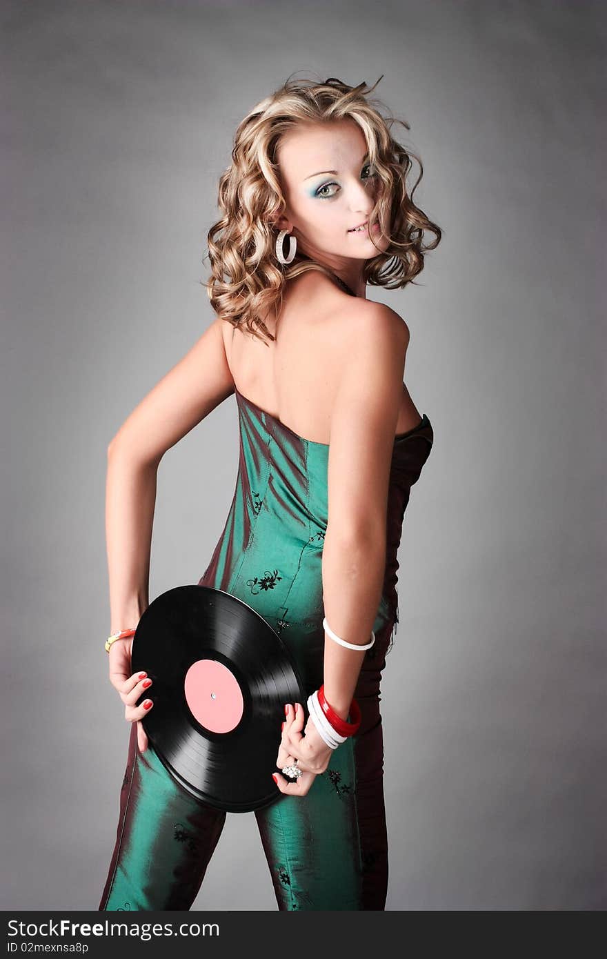 Beautiful girl in trend clothes holding vinyl disc in her hands looking at the photographer.