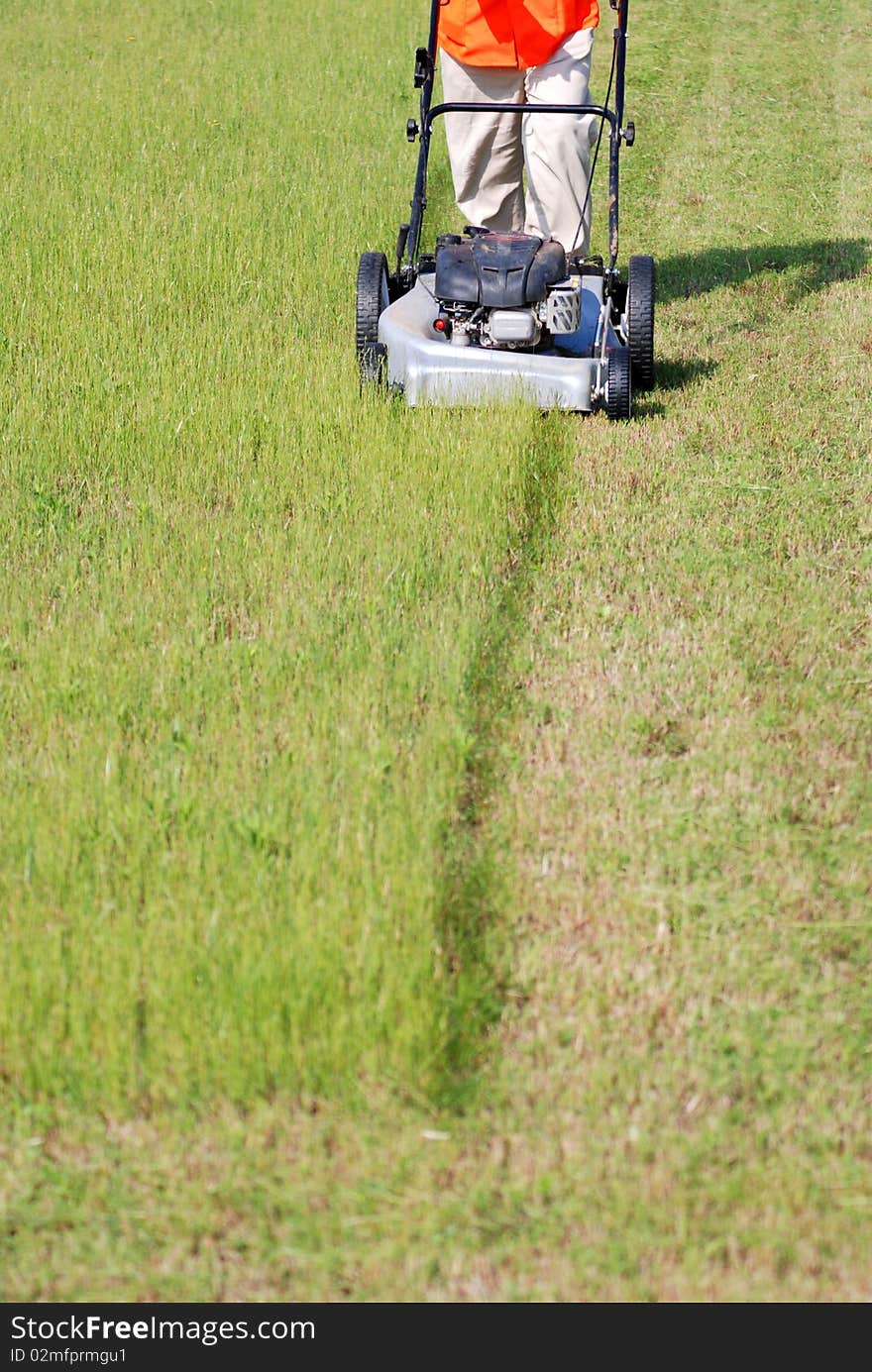 A worker is cutting the grass on the grassy lawn. A worker is cutting the grass on the grassy lawn