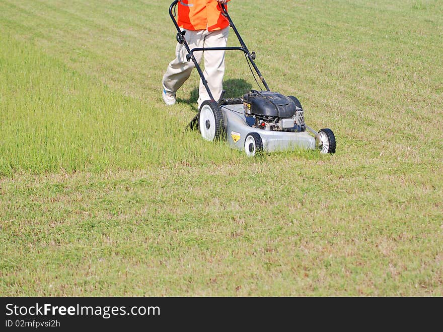 A worker is cutting the grass on the grassy lawn. A worker is cutting the grass on the grassy lawn