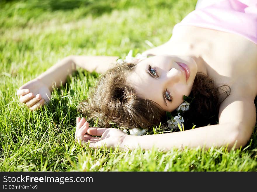 Beautiful girl lying on the grass with flowers