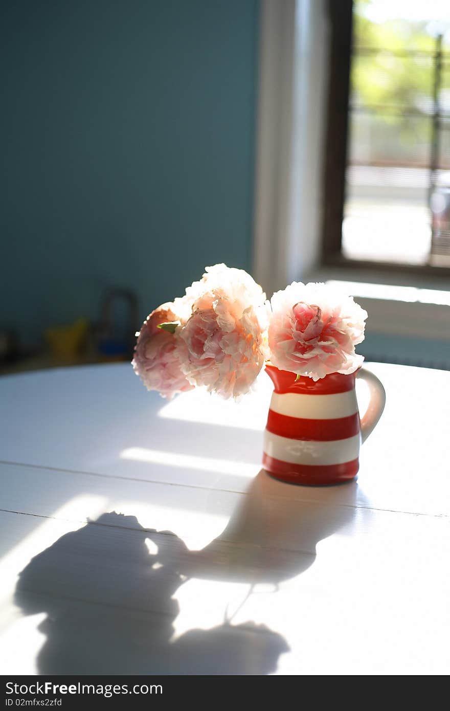 A charming vase of peony flowers in a sunlit kitchen. A charming vase of peony flowers in a sunlit kitchen.