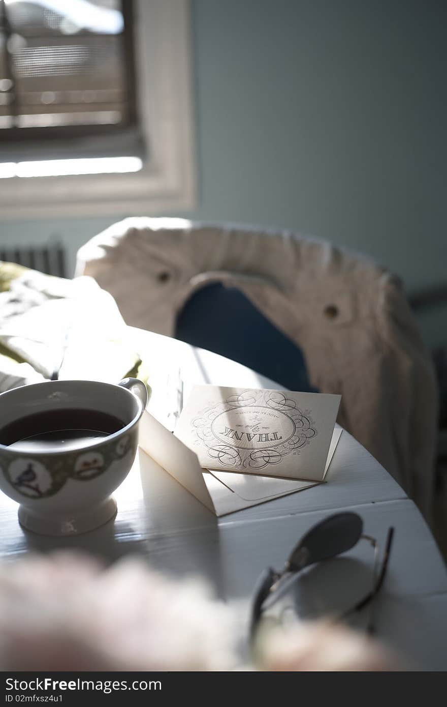 A sunny setting in someone's home where someone has been drinking coffee and writing a note. A sunny setting in someone's home where someone has been drinking coffee and writing a note.