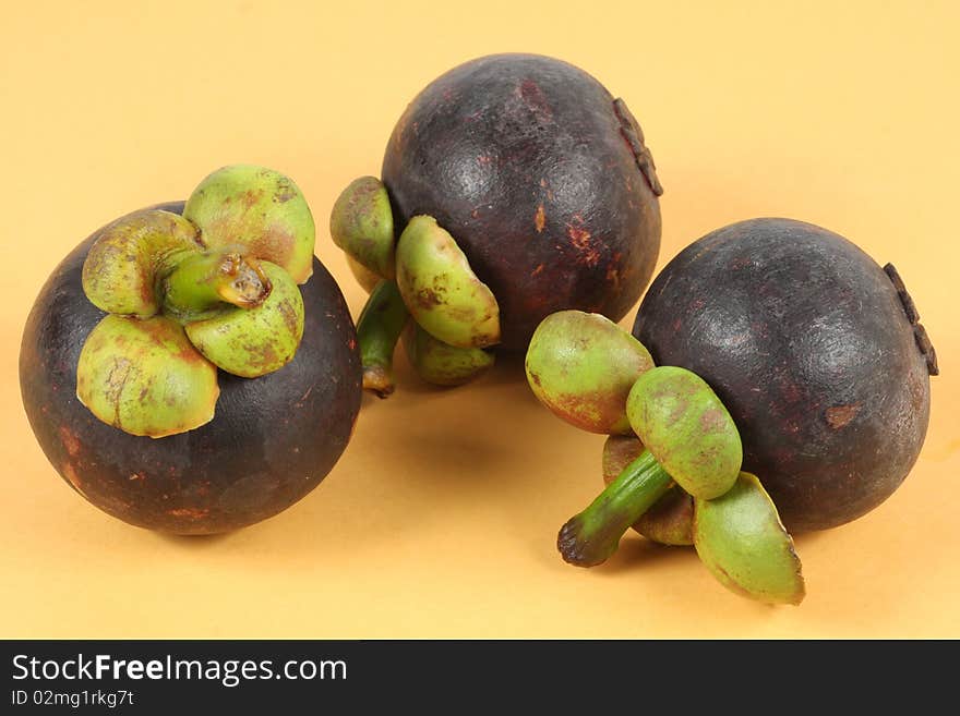 Three Mangosteen on yellow background