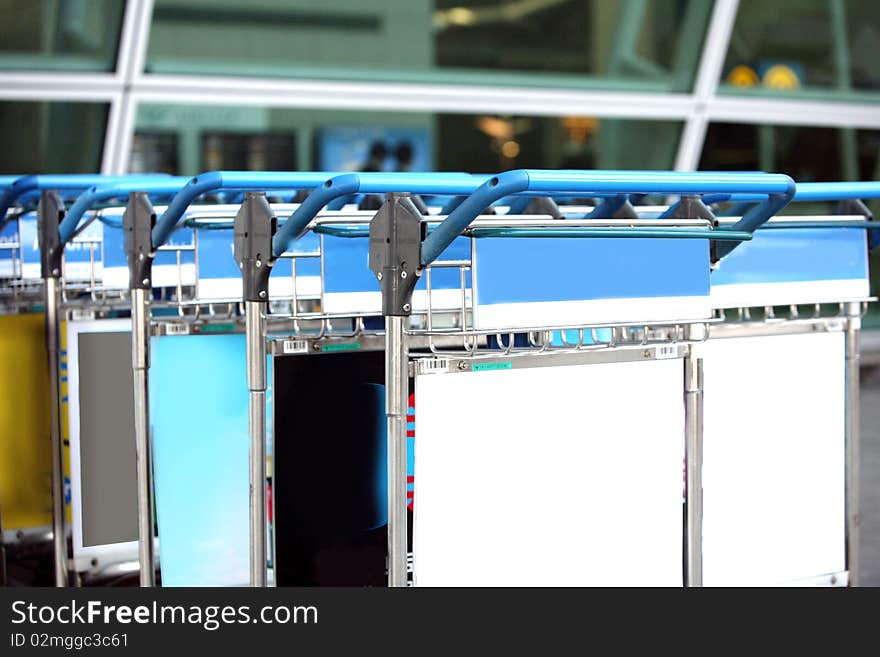 Row of luggage carts at busy airport, with selective focus on the closer carts