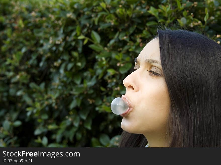 Girl in a park on the green background of foliage, blowing a bubble. Girl in a park on the green background of foliage, blowing a bubble