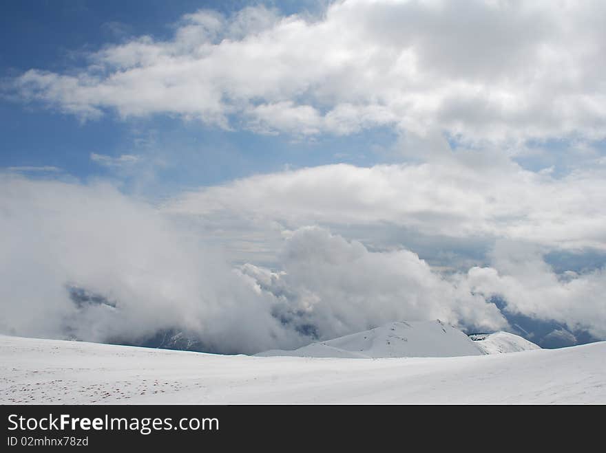 Mountain winter slope in clouds.