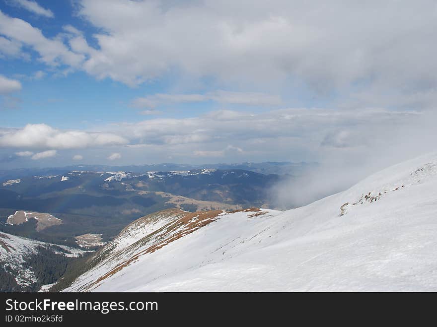 Mountain winter slope in clouds.