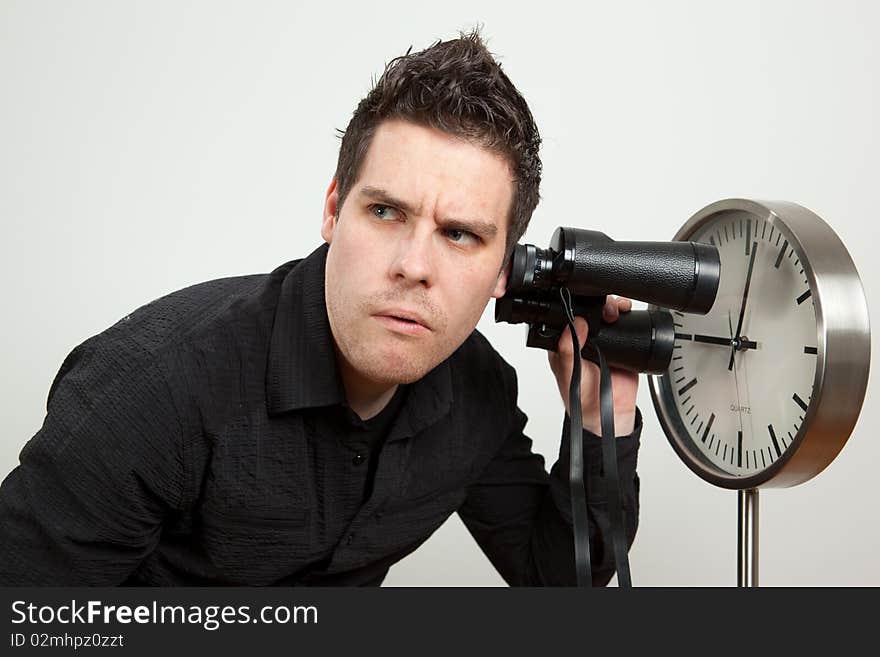 Guy holding binoculars and listening the clock. Guy holding binoculars and listening the clock