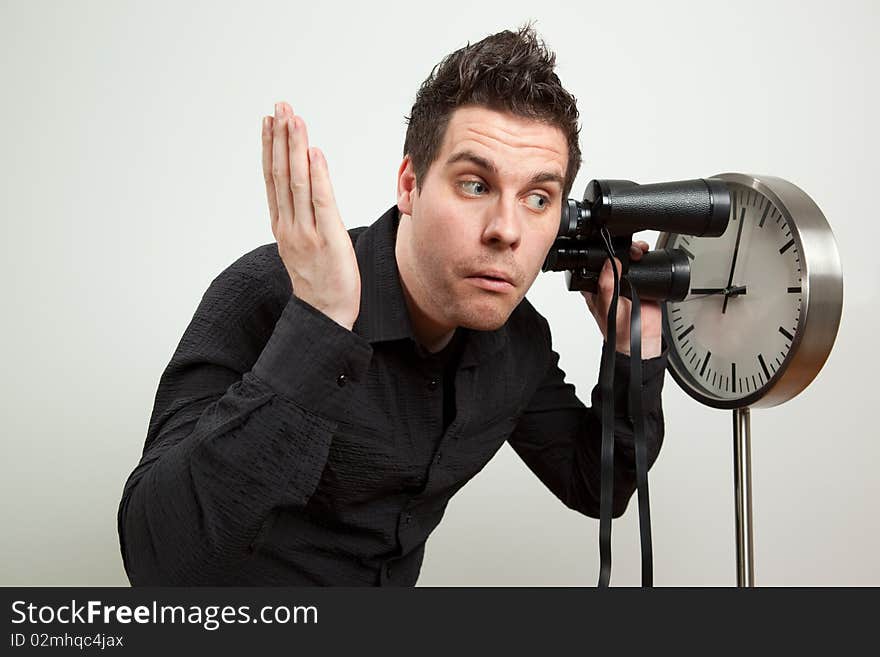 Guy holding binoculars and listening the clock. Guy holding binoculars and listening the clock