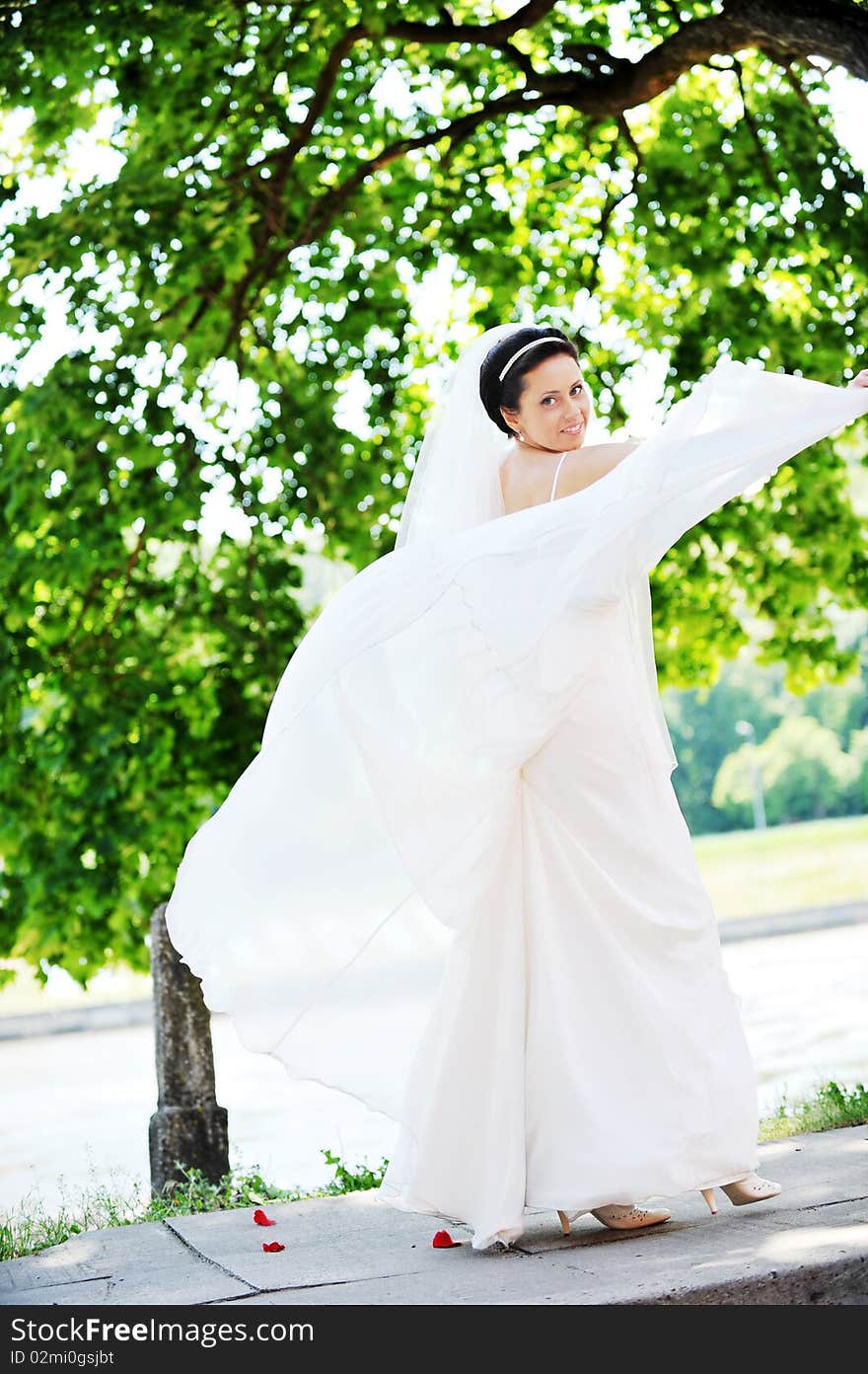 Bride in white dress on background of green trees