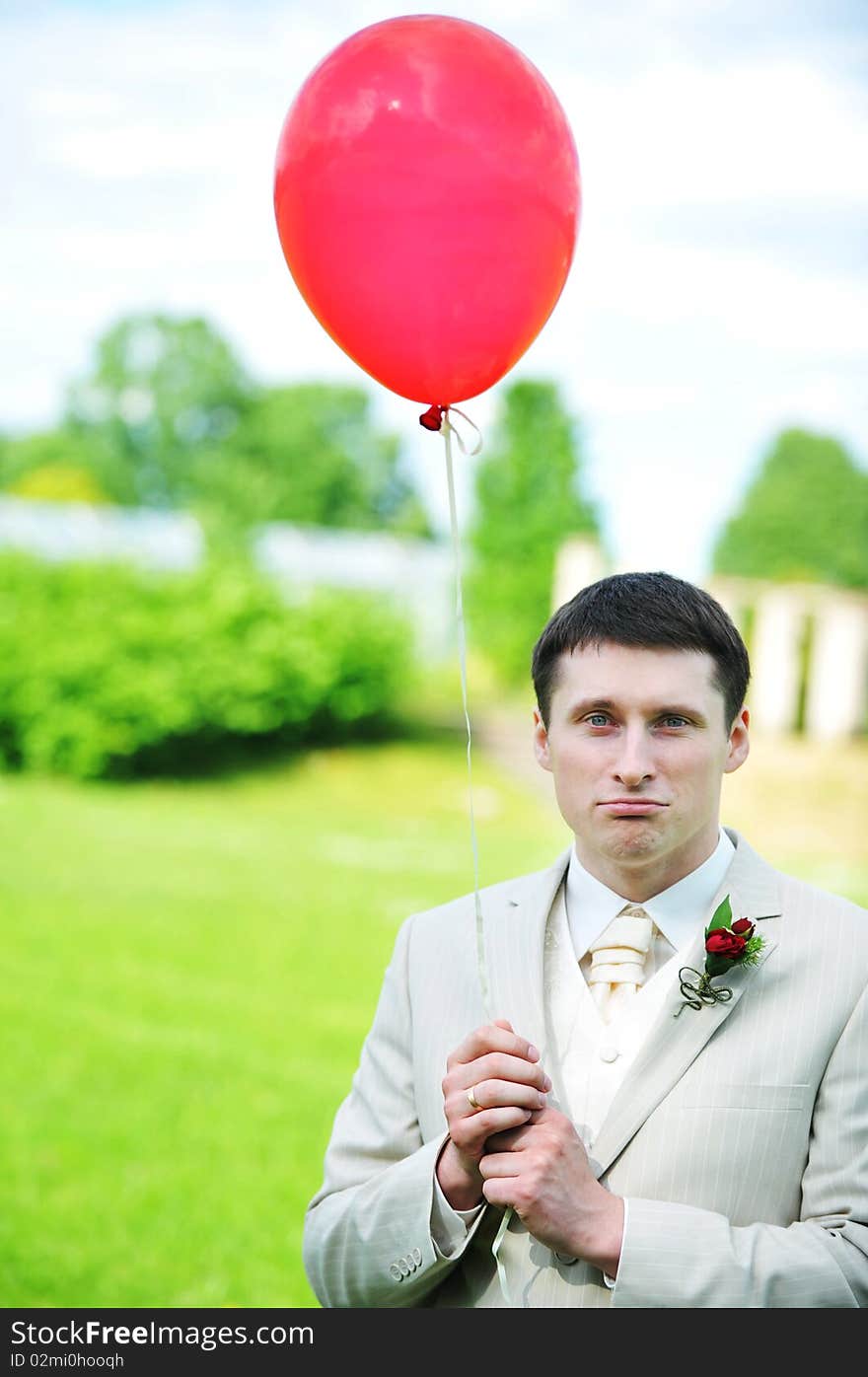 Young groom with balloon on green field. Young groom with balloon on green field