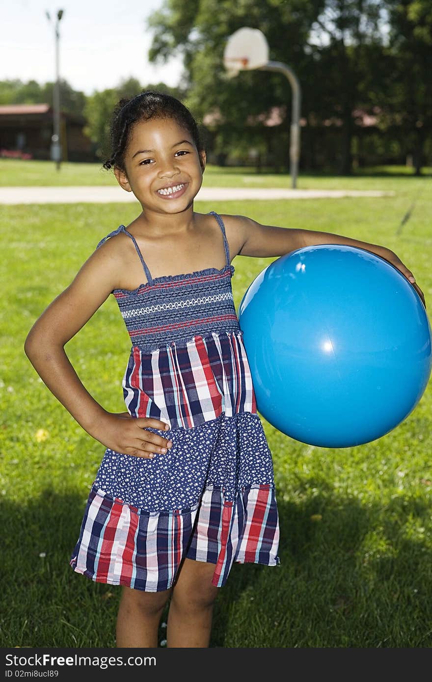 Little girl holding big blue ball at the playground, smiling. Little girl holding big blue ball at the playground, smiling