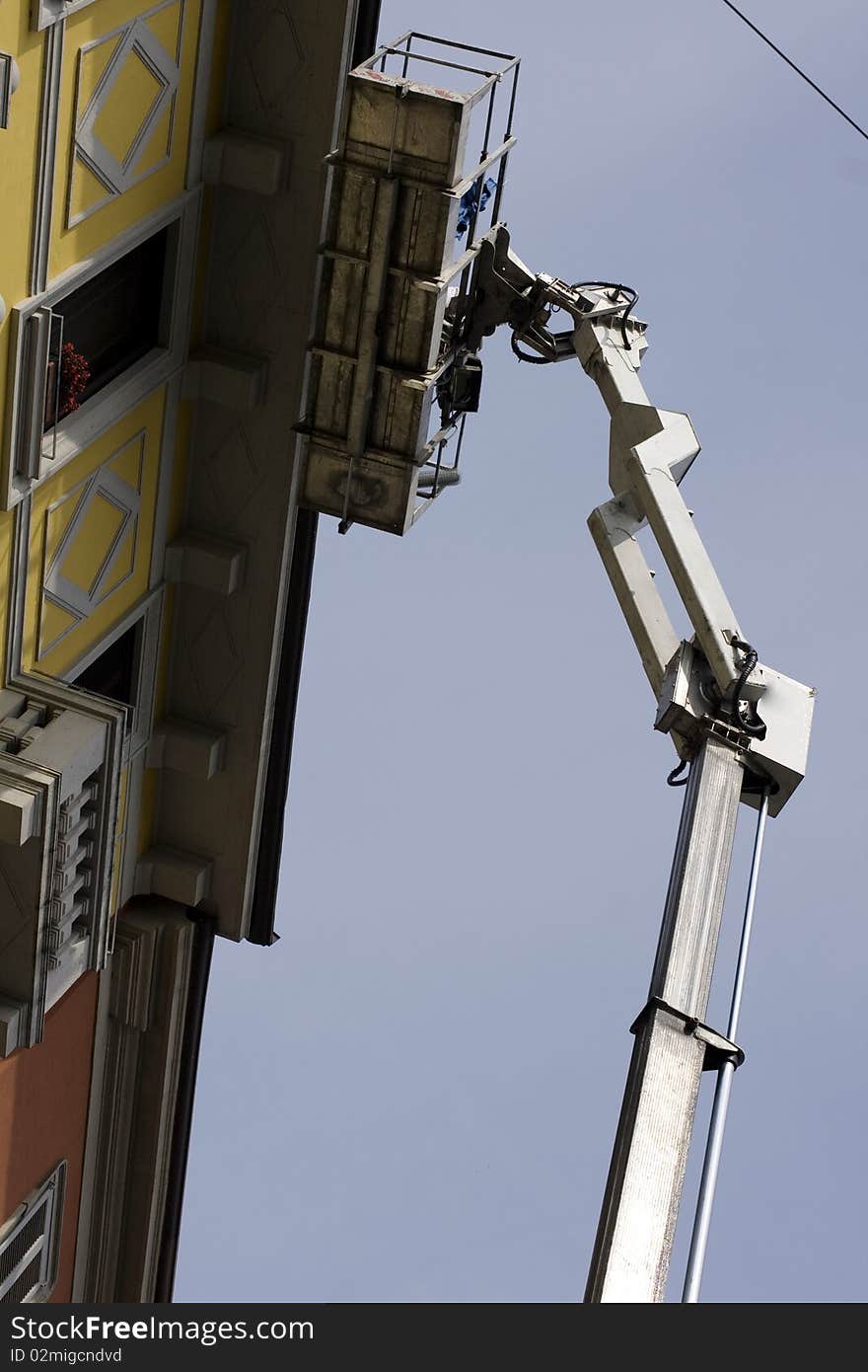 Workers restoring a building on a crane. Workers restoring a building on a crane