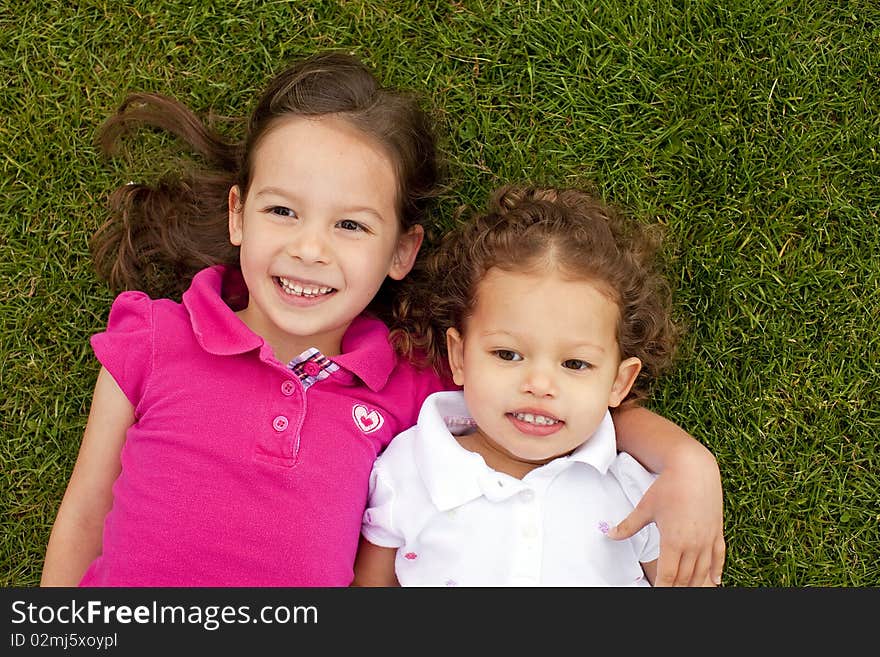 Cute little sisters laying in grass