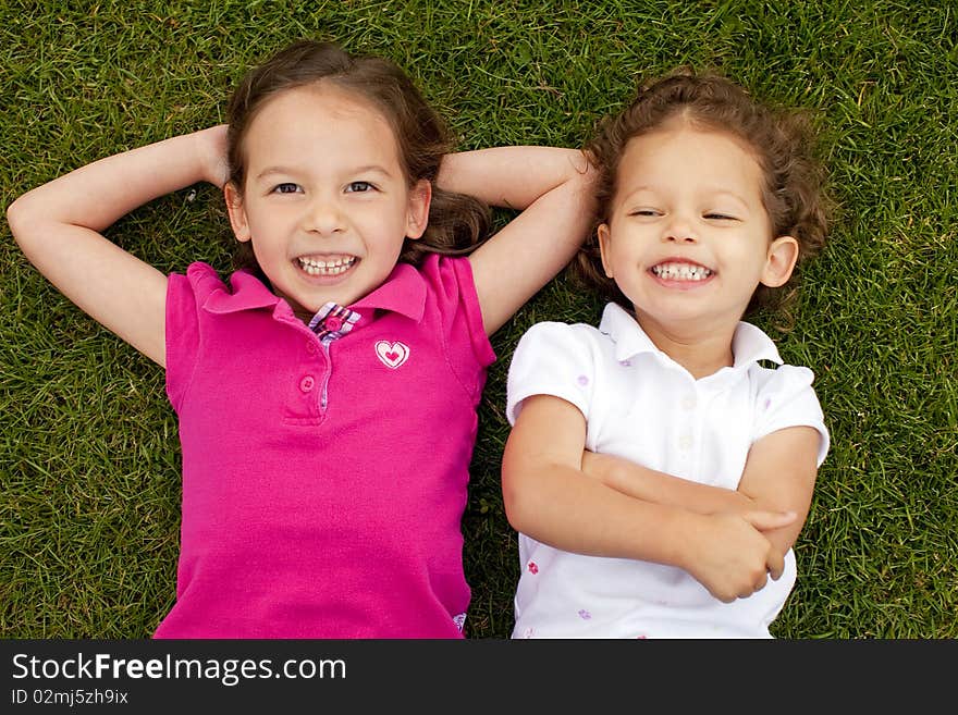 Cute little sisters laying in grass