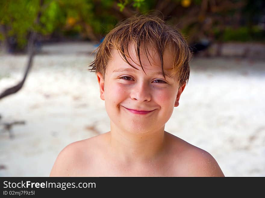 Happy boy with wet hair at the beach smiles