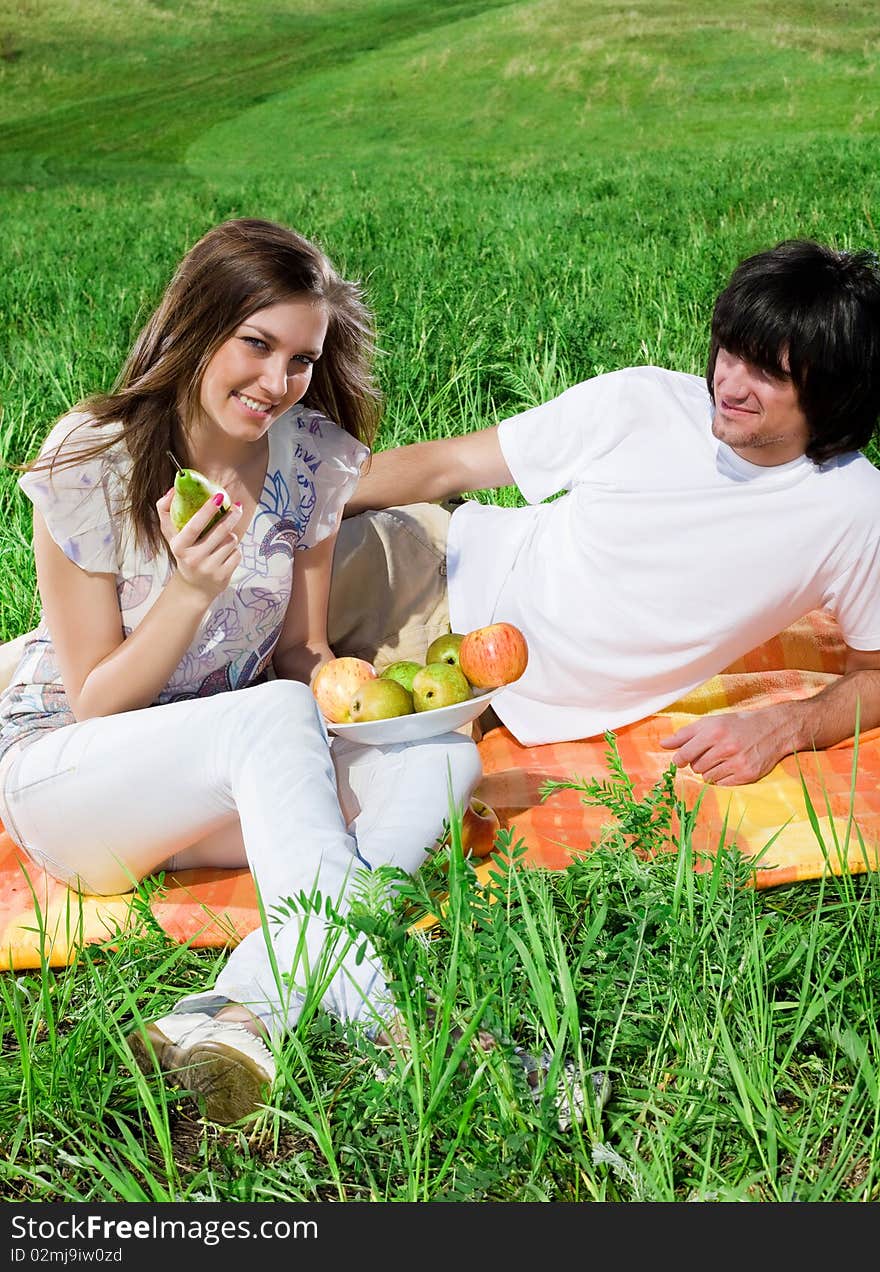 Girl with fruit and boy with smile on grass