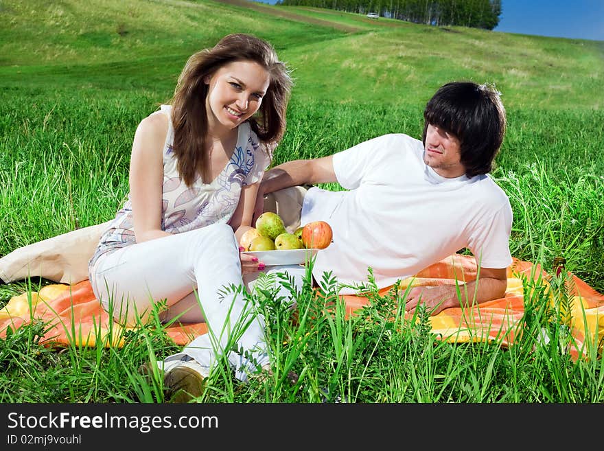 Girl with fruits and boy on grass