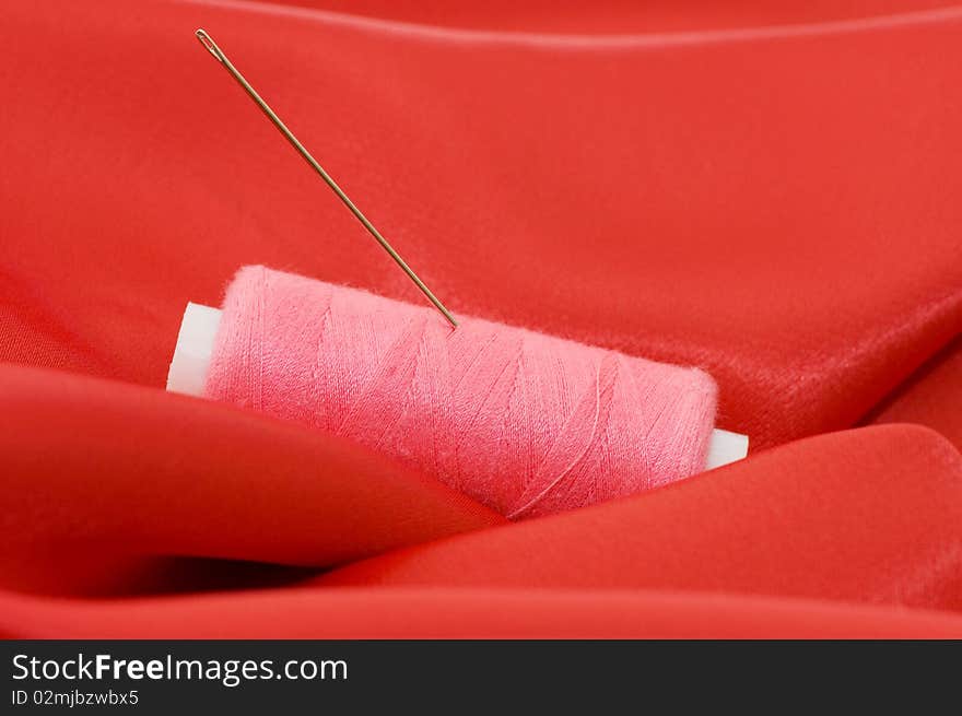 Ball of threads on a red fabric close up