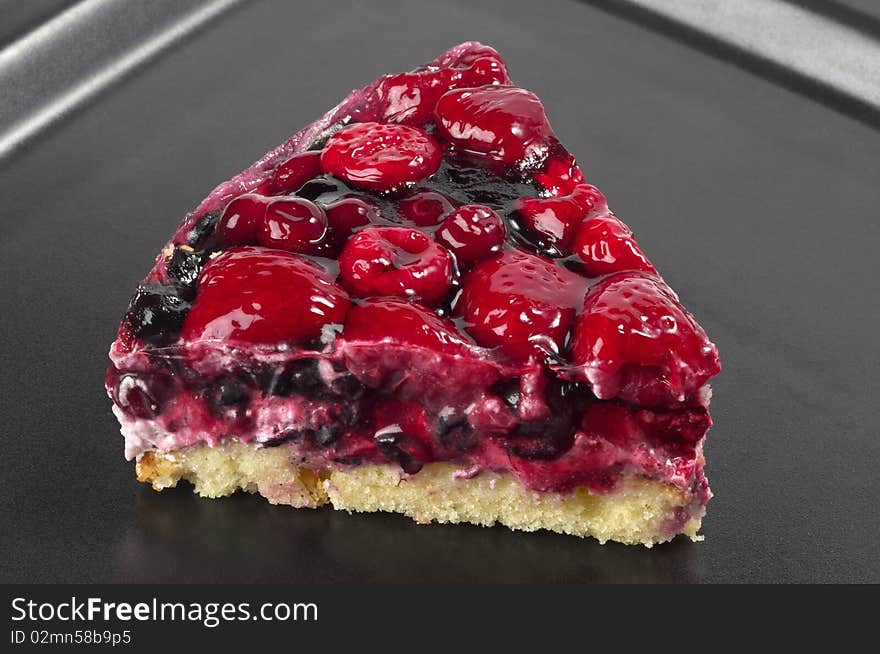 Small berries tart piece macro shot over black background