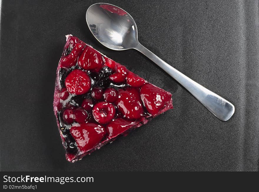 Small berries tart piece macro shot over black plate