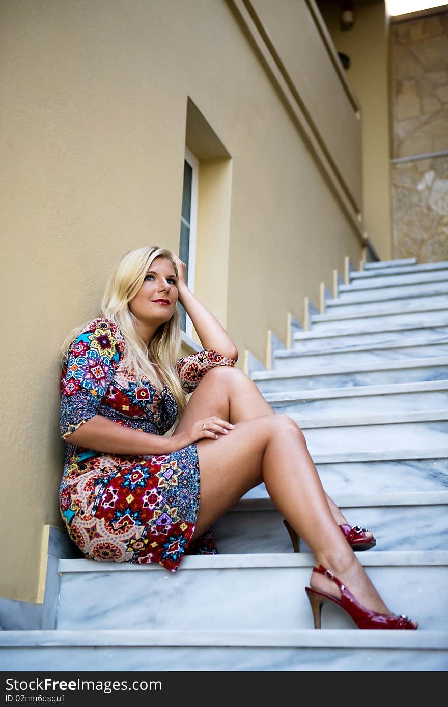 Young beautiful summer woman sitting on the hotel stairs outdoors. Young beautiful summer woman sitting on the hotel stairs outdoors