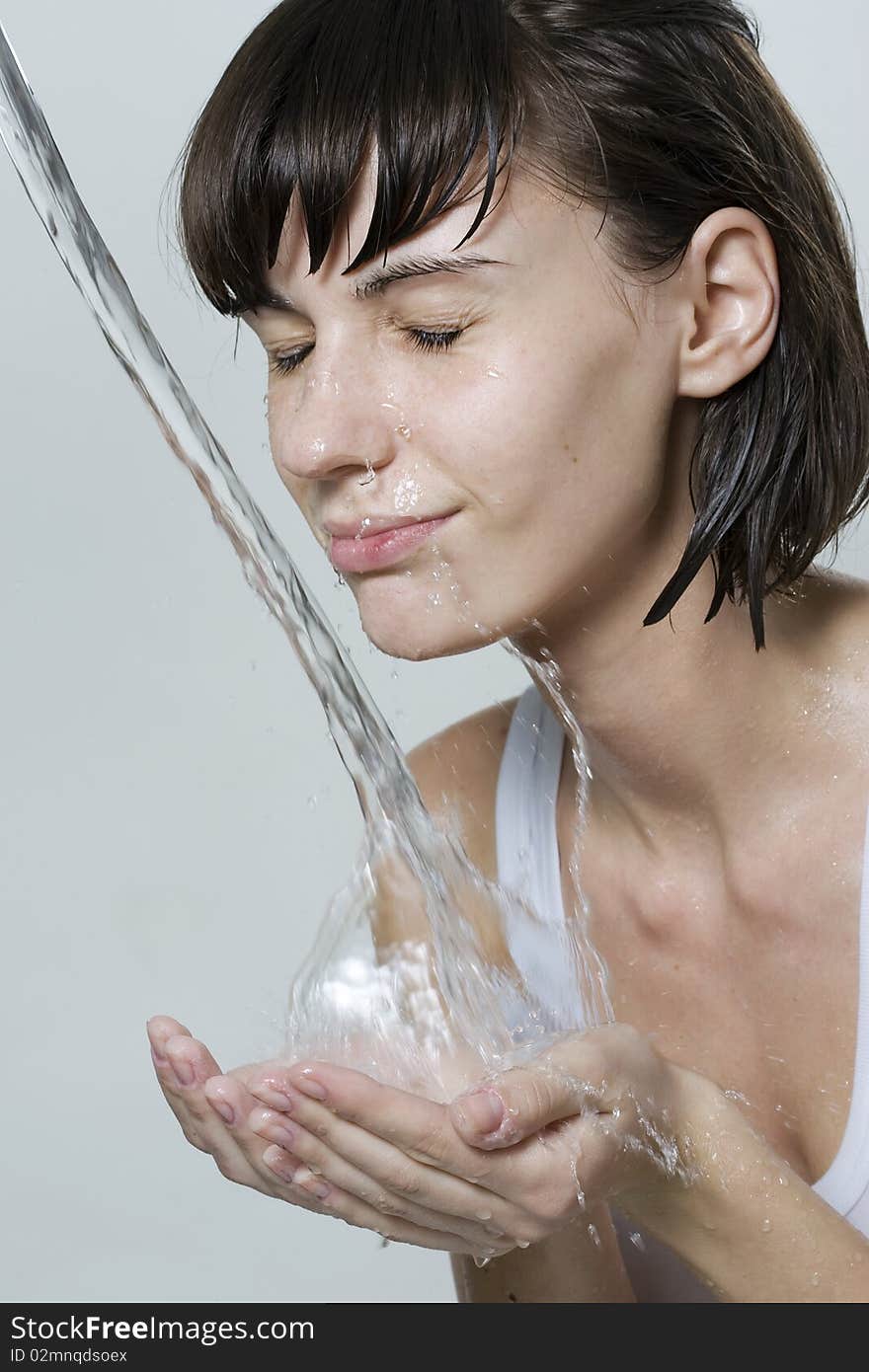 Happy beautiful woman wash her face with pure water. Happy beautiful woman wash her face with pure water