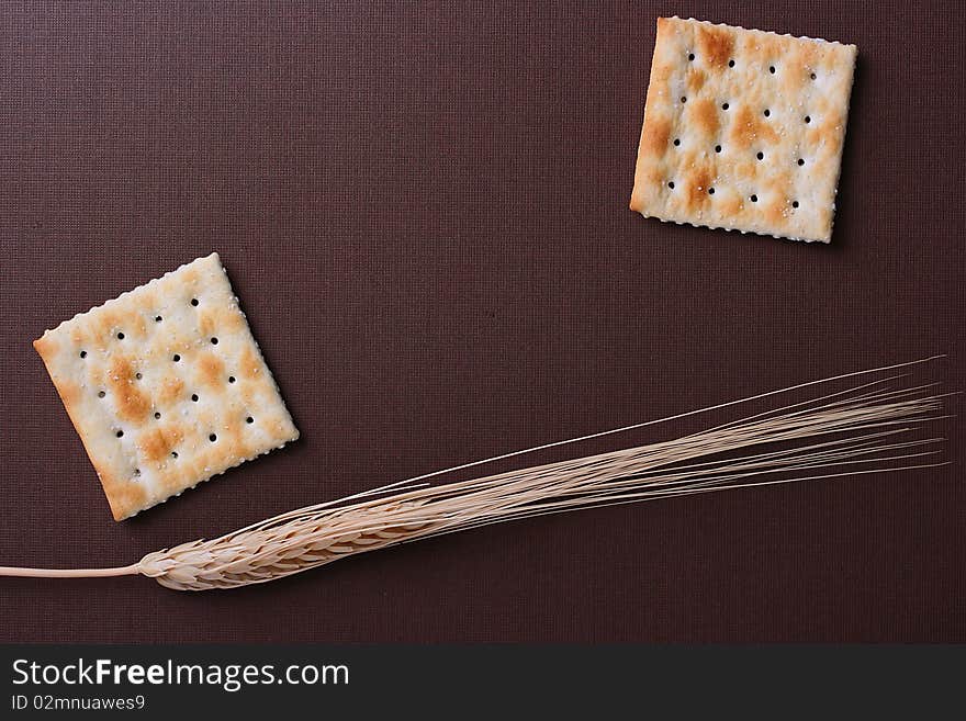 Fresh cookies strewed by salt on a brown background with a dry cone.