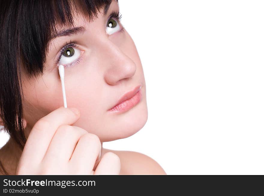 Beautiful young girl removing makeup from eyes with cotton bud isolated on white