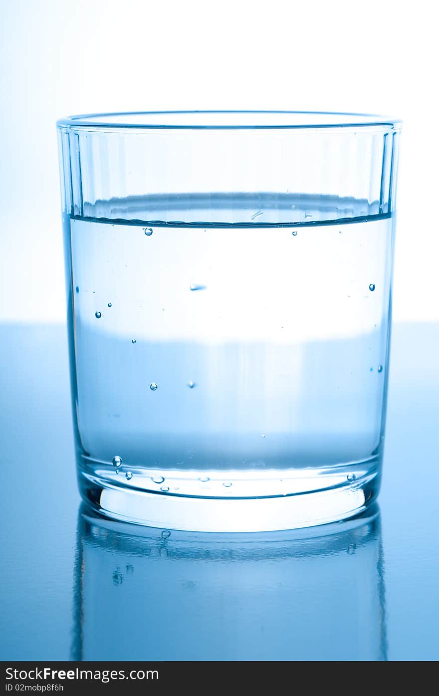 Glass with water on glossy background