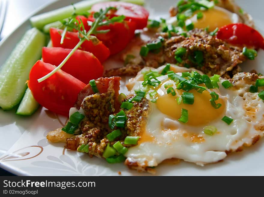 Close-up breakfast - fried eggs with bacon, french mustard, green onion and fresh vegetables. Close-up breakfast - fried eggs with bacon, french mustard, green onion and fresh vegetables