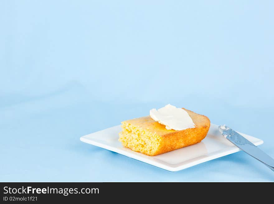 Piece of corn bread with butter on small plate. Piece of corn bread with butter on small plate