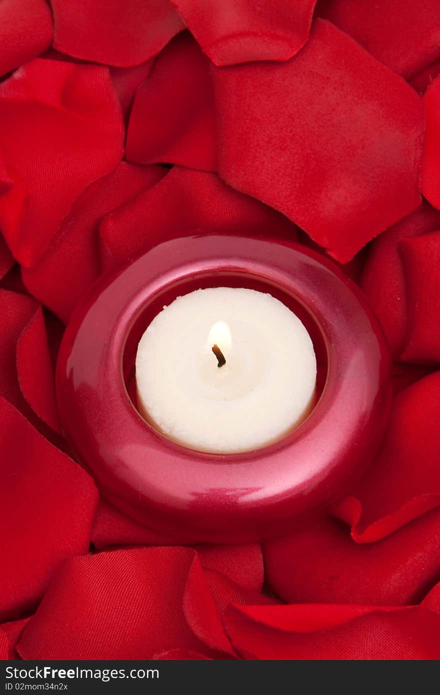 Candle surrounded with red rose petals. Candle surrounded with red rose petals