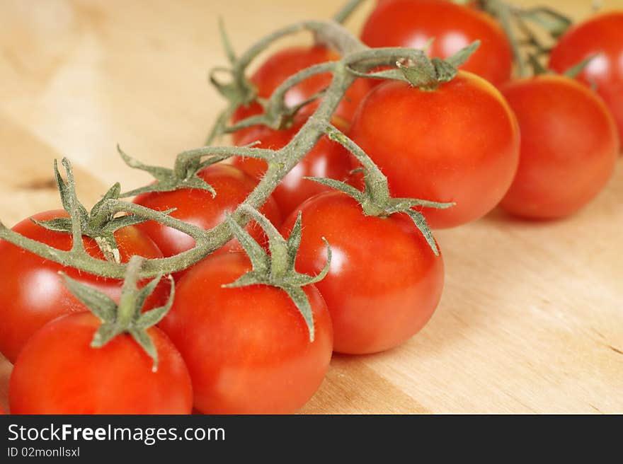 Fresh organic cherry tomatoes on a wooden cutting board. Studio shot. Selective focus, shallow DOF.