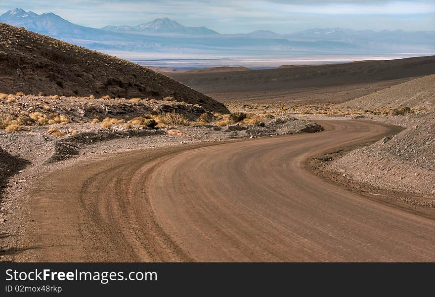 A curve in the middle of the desert, with mountains behind. A curve in the middle of the desert, with mountains behind