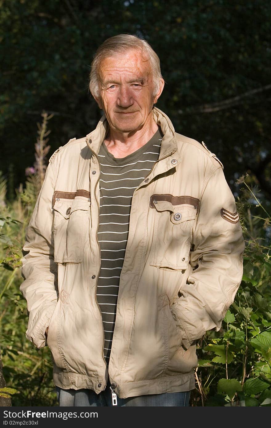 Portrait of the grey-haired elderly man in a beige jacket in village on the nature. Portrait of the grey-haired elderly man in a beige jacket in village on the nature