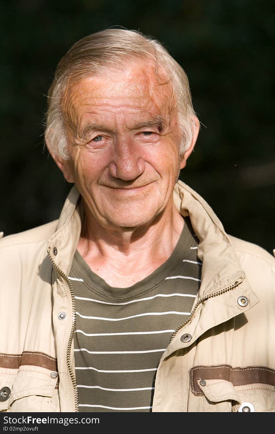 Portrait of the grey-haired elderly man in a beige jacket in village on the nature. Portrait of the grey-haired elderly man in a beige jacket in village on the nature