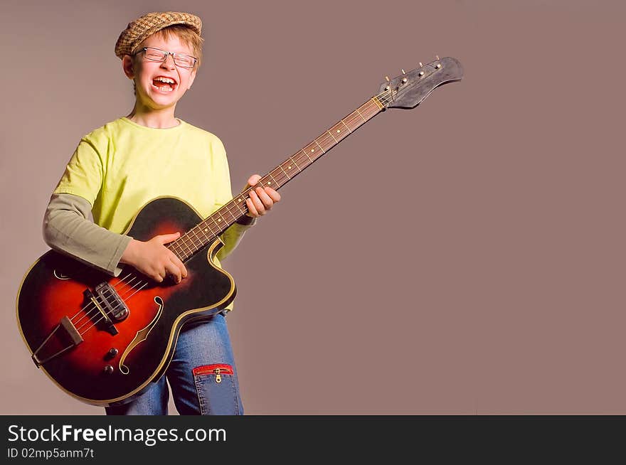 The young boy emotionally plays on a guitar. The young boy emotionally plays on a guitar