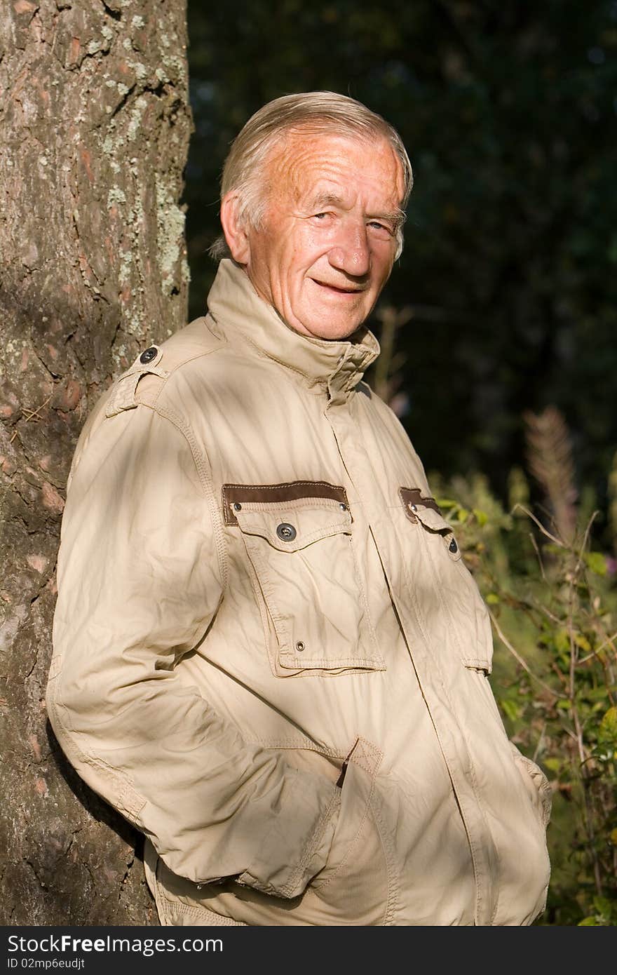 Portrait of the grey-haired elderly man in a beige jacket in village on the nature. Portrait of the grey-haired elderly man in a beige jacket in village on the nature