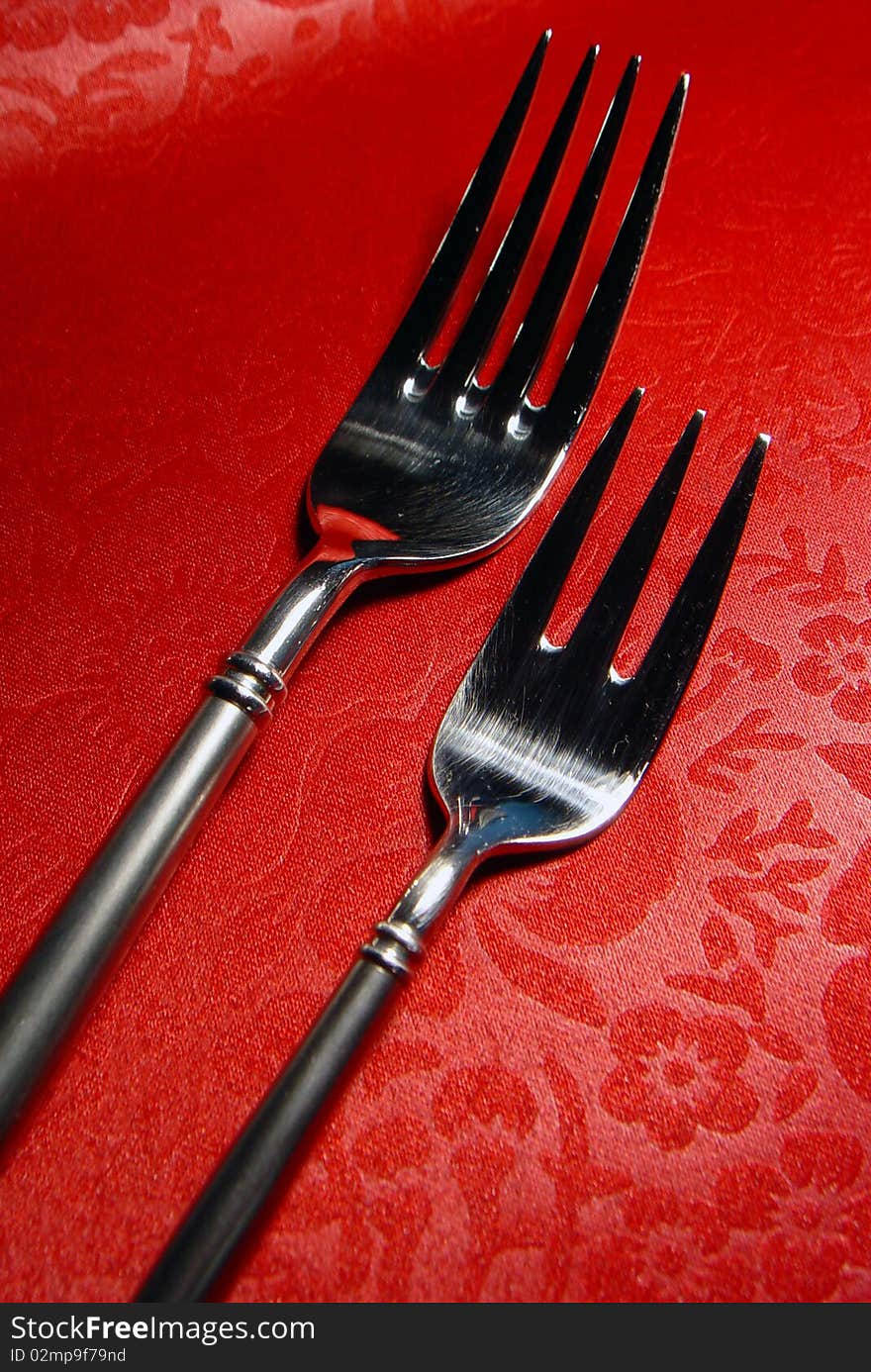 Two forks with red leather background