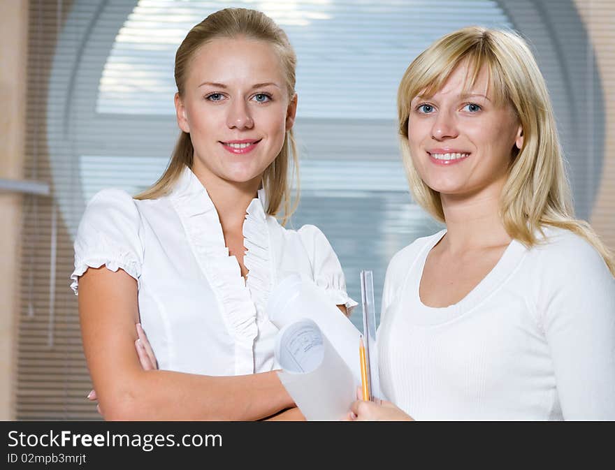 Portrait of two young beautiful business women in front of windows with shutters. Portrait of two young beautiful business women in front of windows with shutters