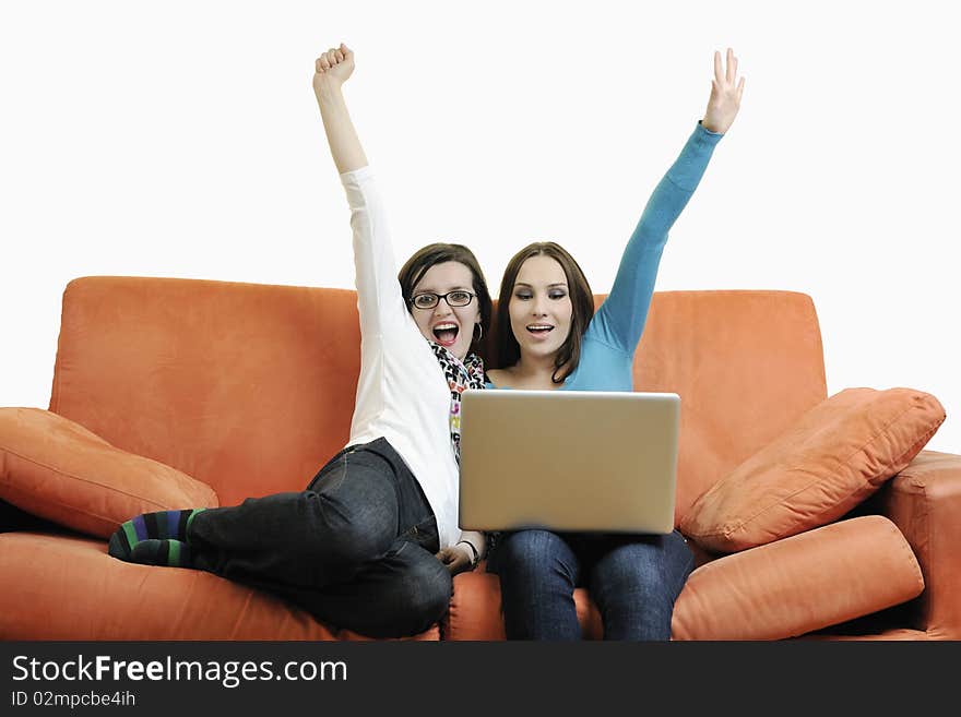 Two happy young woman working on laptop computer on red sofa isolated on white. Two happy young woman working on laptop computer on red sofa isolated on white