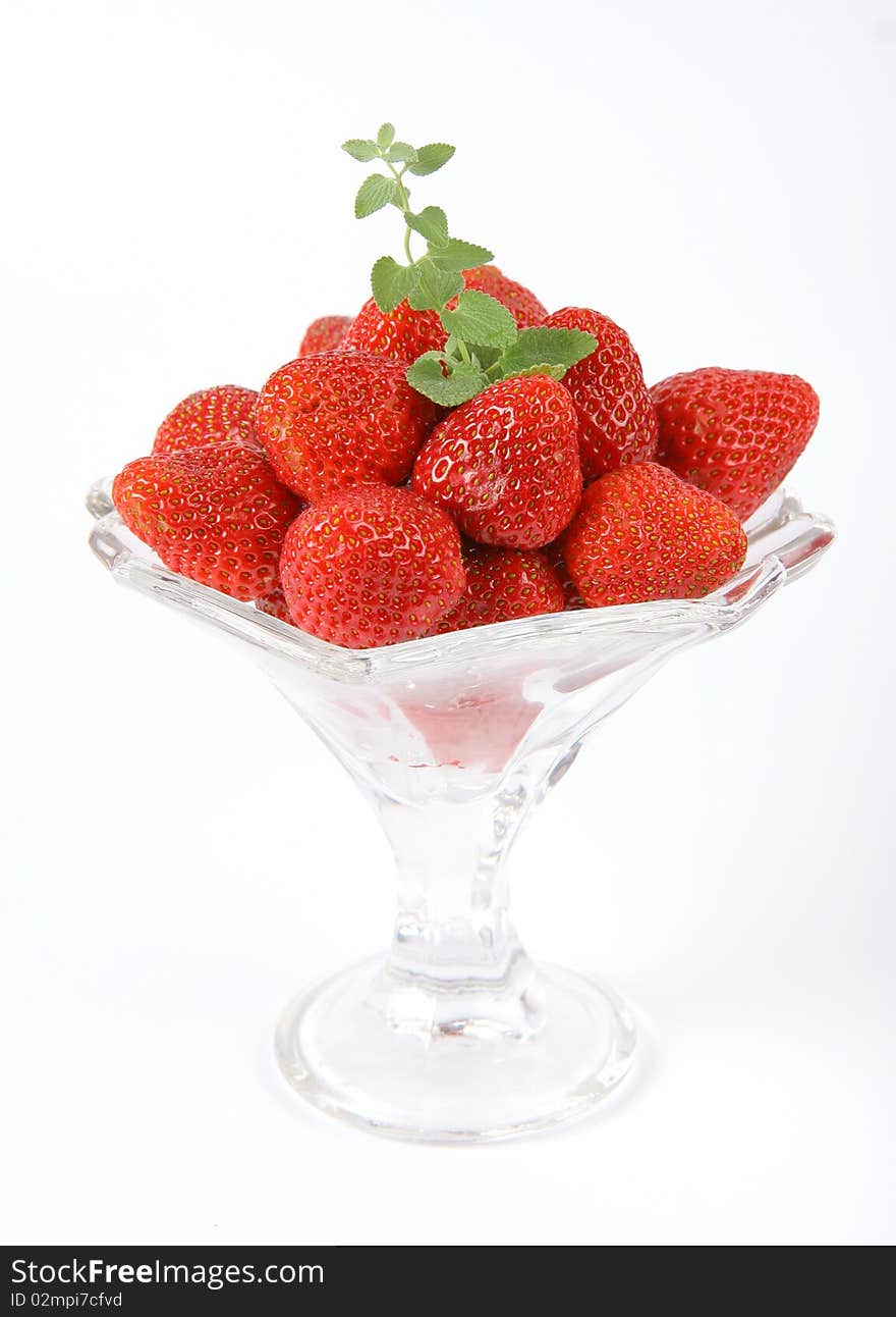 Strawberries in a cup decorated with a lemon balm twig on white background. Strawberries in a cup decorated with a lemon balm twig on white background