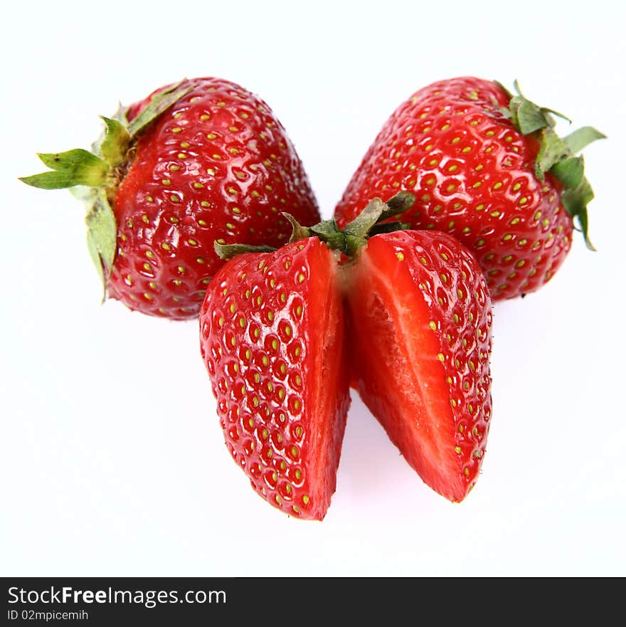 Strawberries on white background (two whole ones and one cut in half)